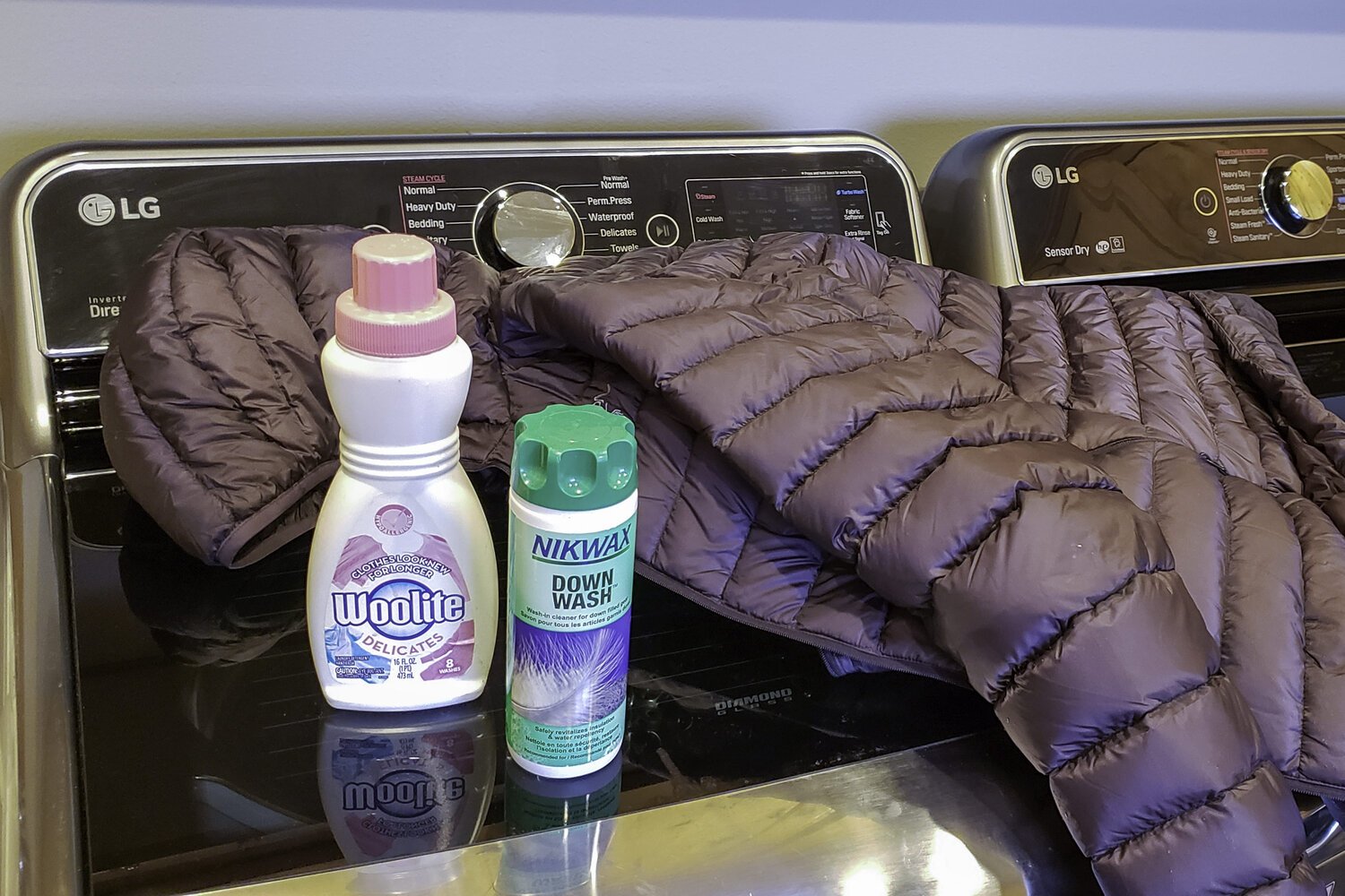 A down jacket and some technical fabric wash sitting on a washing machine