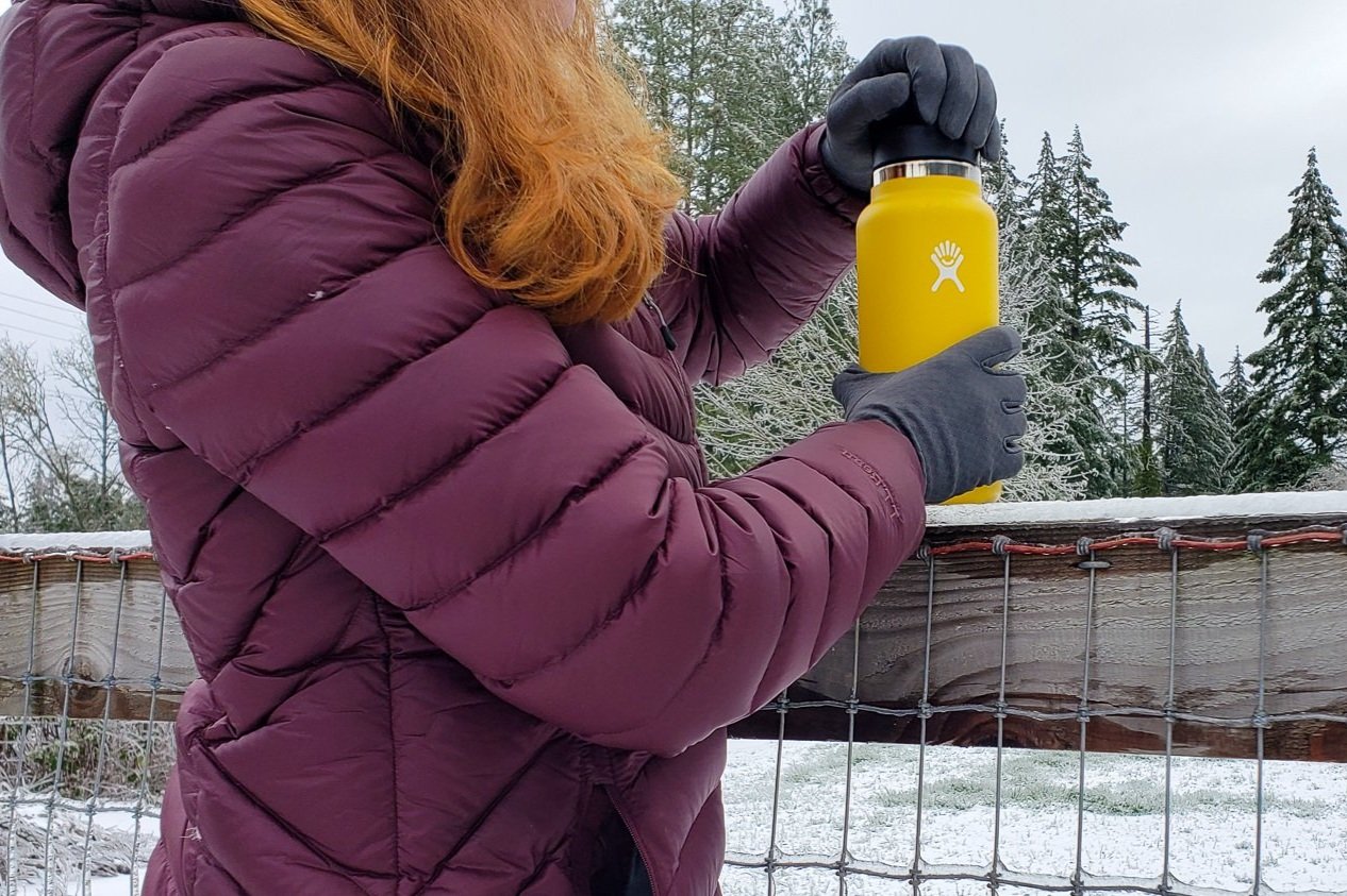 A person with gloves on unscrewing the lid of a Hydro Flask Wide Mouth Vacuum Bottle