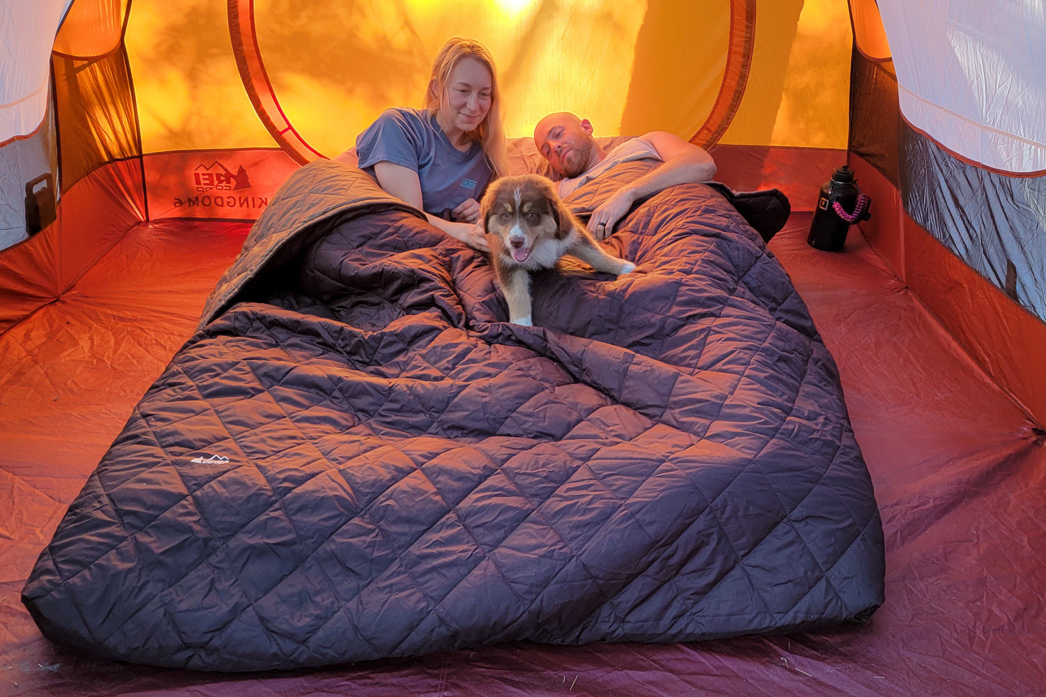The REI Co-op Kingdom Sleep System 40 includes a queen-size inflatable air mattress, a fitted sheet set, & a thin quilted blanket to make a complete camping bed.