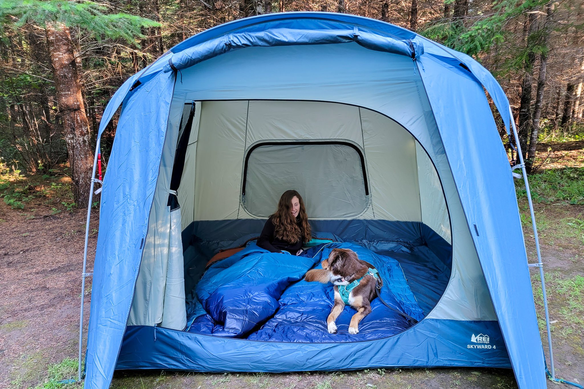 A girl and her dog in a tent with the 2-Person Rumpl Original Puffy Blanket