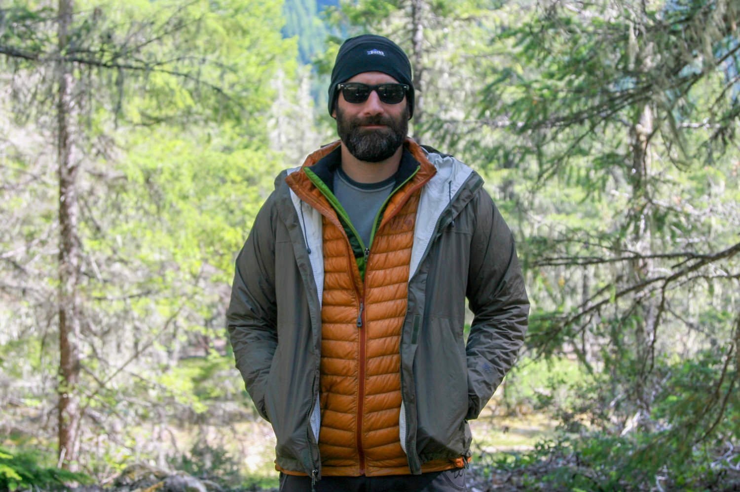 A backpacker with a fleece, down jacket, and rain jacket layered over the Patagonia Capilene Midweight Base Layer Top
