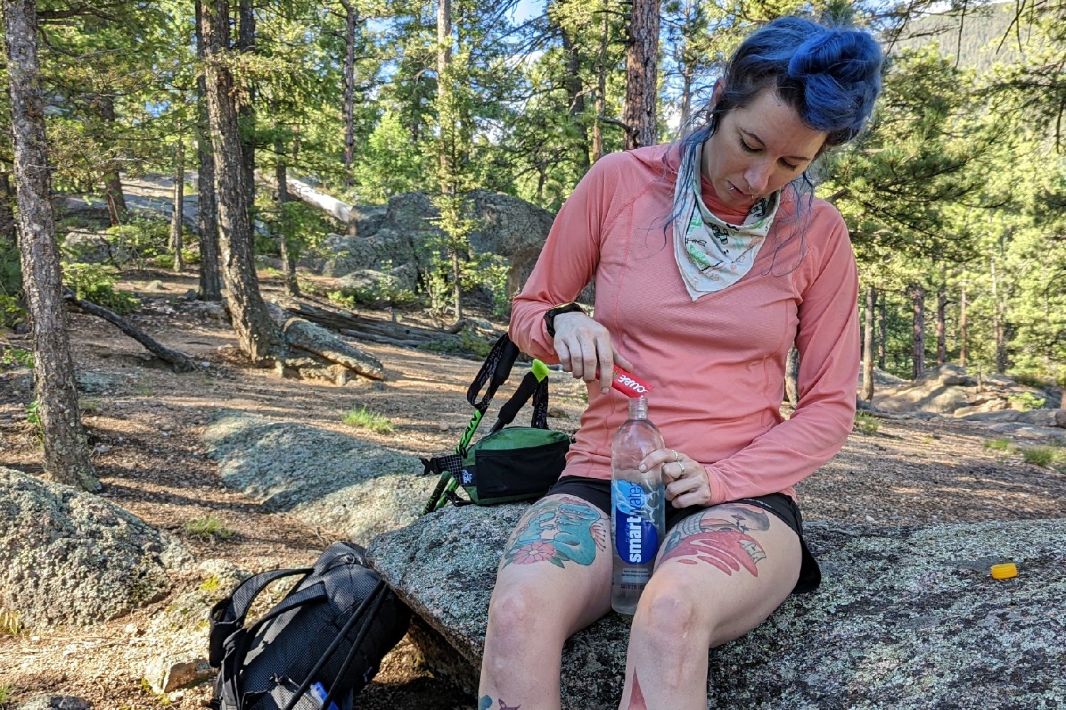 A hiker pouring cure hydration mix into a Smartwater Bottle on a trail