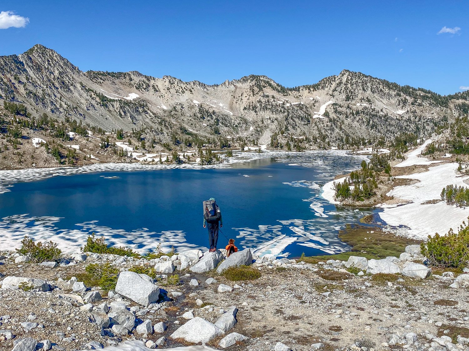A hiker wearing the Mountain Hardwear Trail Sender Hiking Pants looking out over a partially frozen lake in the mountains
