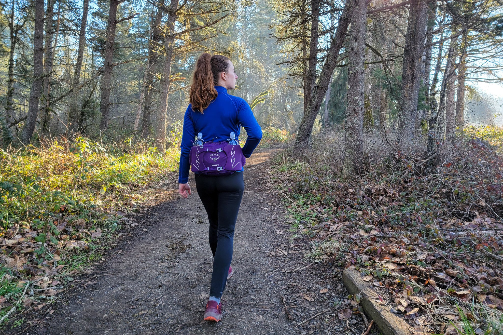 A hiker wearing the Osprey Tempest Waist pack on a foggy wooded trail