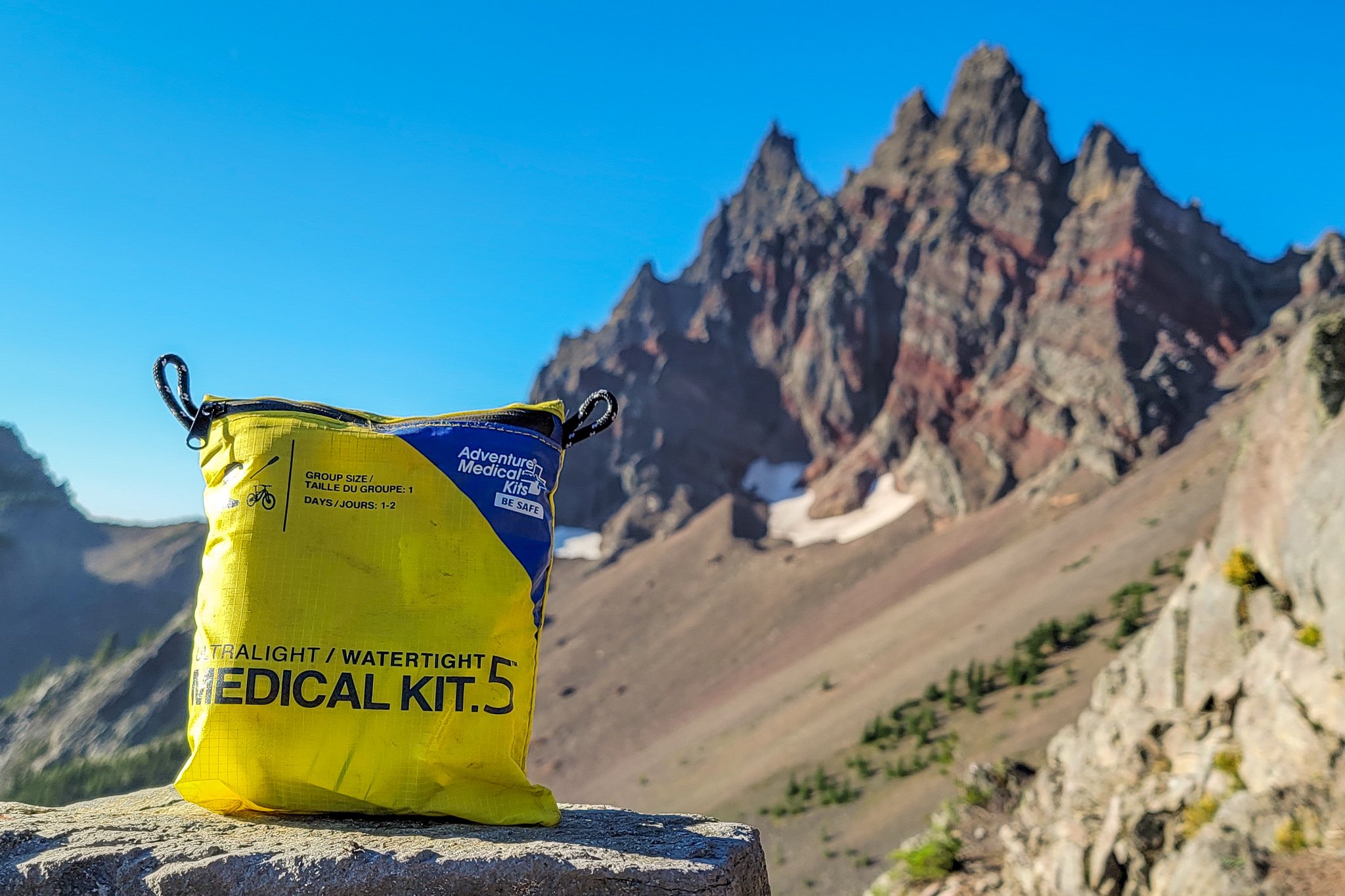 Closeup of the AMK Ultralight/Watertight .5 First Aid Kit in front of a craggy mountain peak - Three Fingered Jack