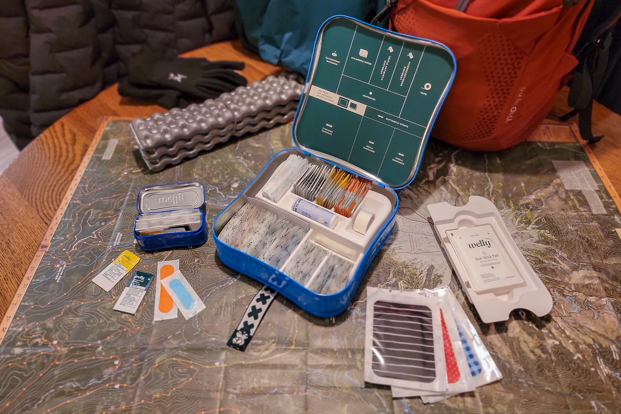 The Welly Excursion and Quick Fix First Aid Kits laid out over a map on the dining room table
