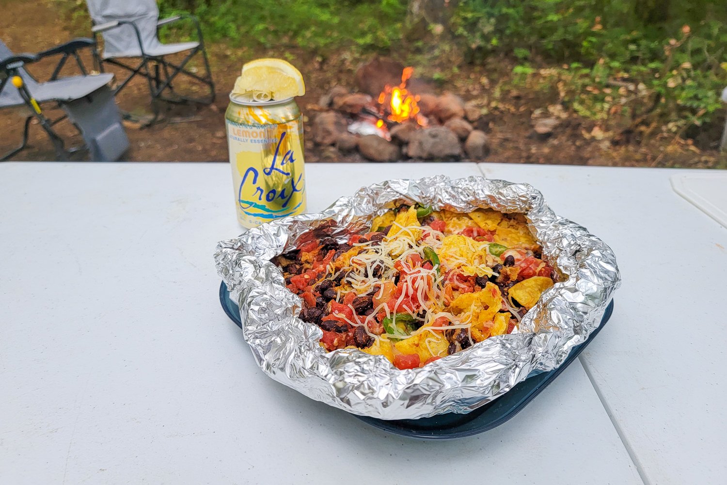 Nachos foil packet meal with a lemon seltzer water and a fire in the background