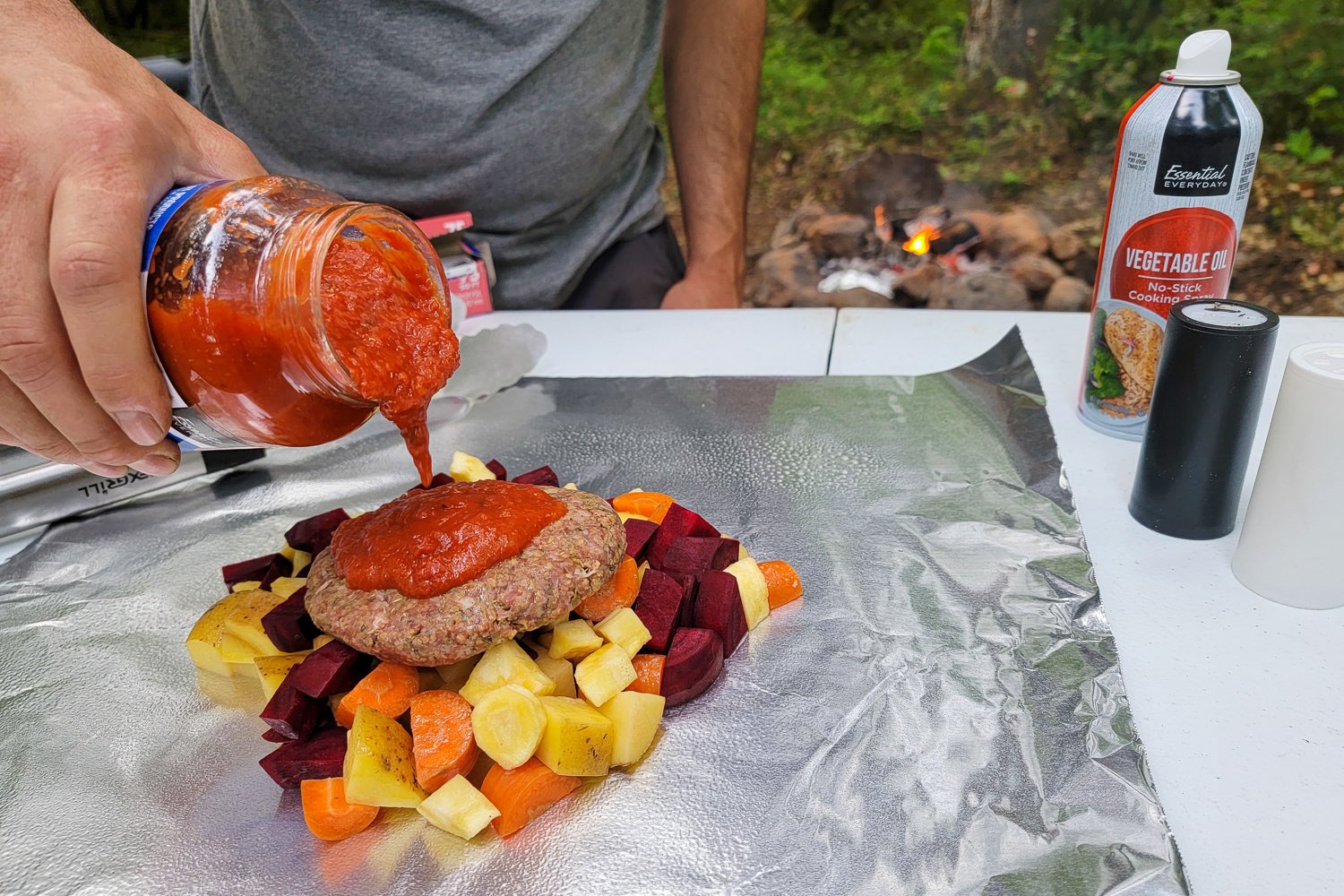 Pouring marinara sauce on top of a meat patty for the meatloaf and roasted veggies recipe