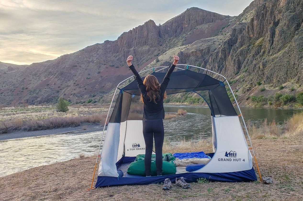 A camping stretching her arms overhead in the Patagonia Capilene Midweight Base Layer Top