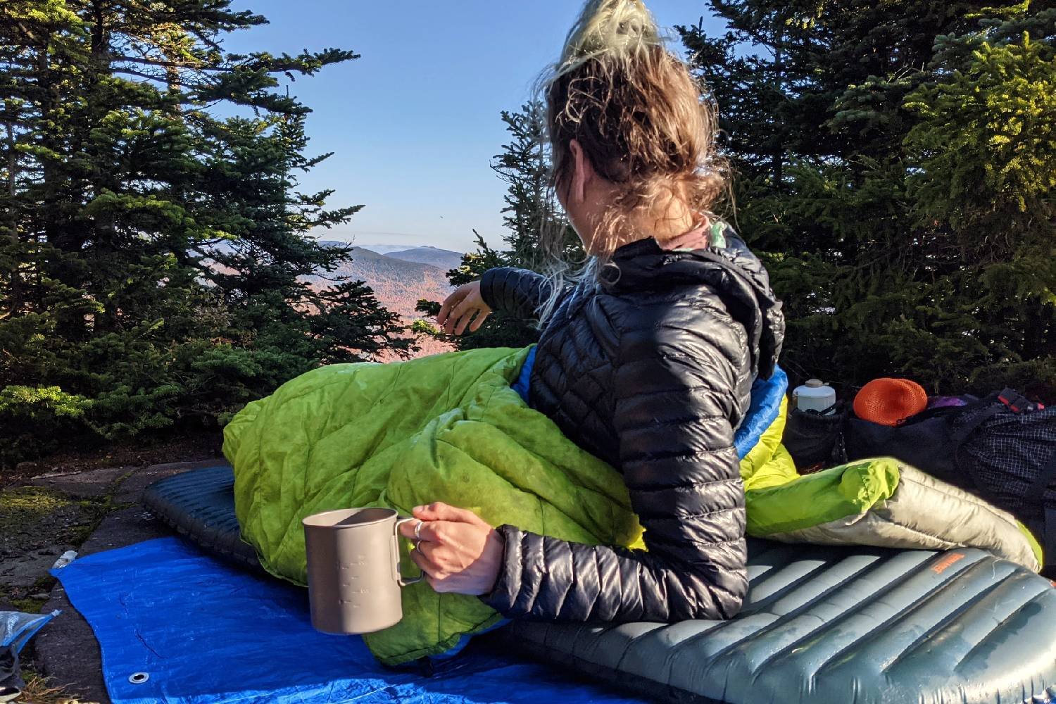 A hiker laying in the Loco Libre Ghost Pepper quilt looking at a mountain view