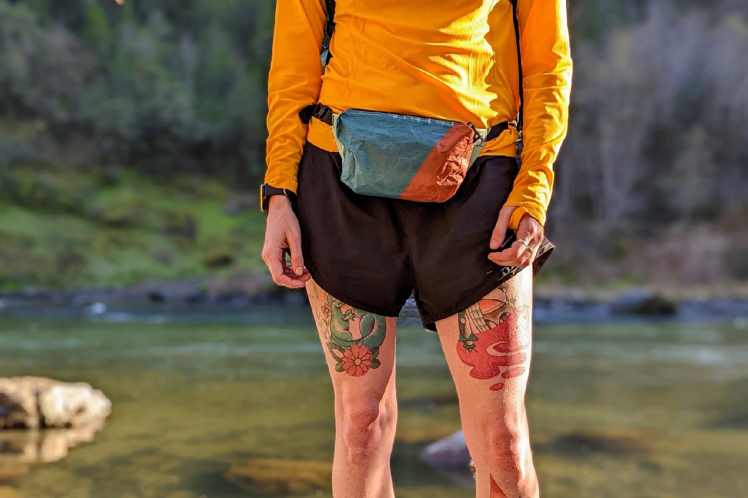 A hiker wearing the Hightail Designs Ultralight Fanny Pack in front of a river