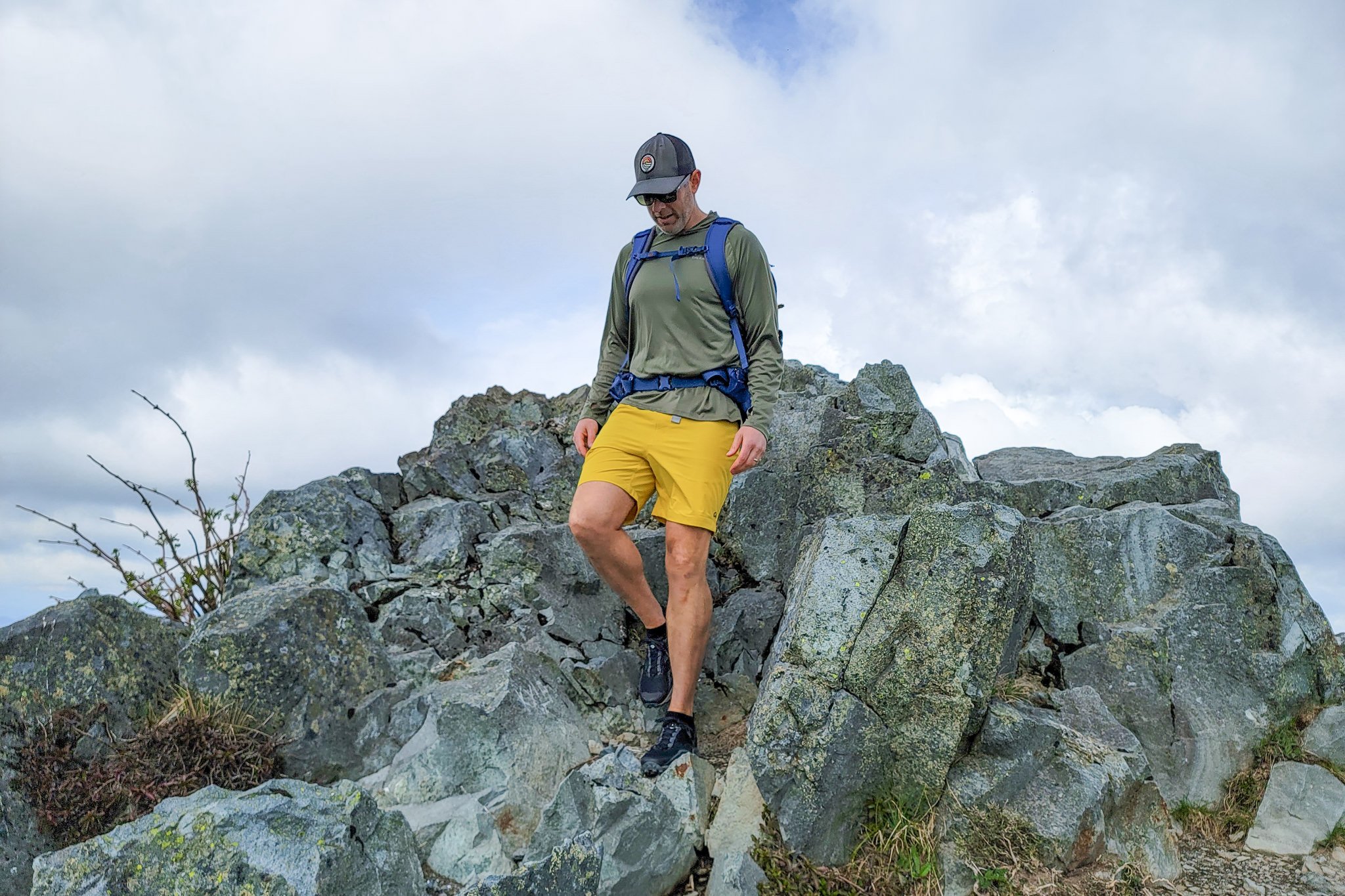 A hiker coming down some rocks wearing Outdoor Research Ferrosi shorts