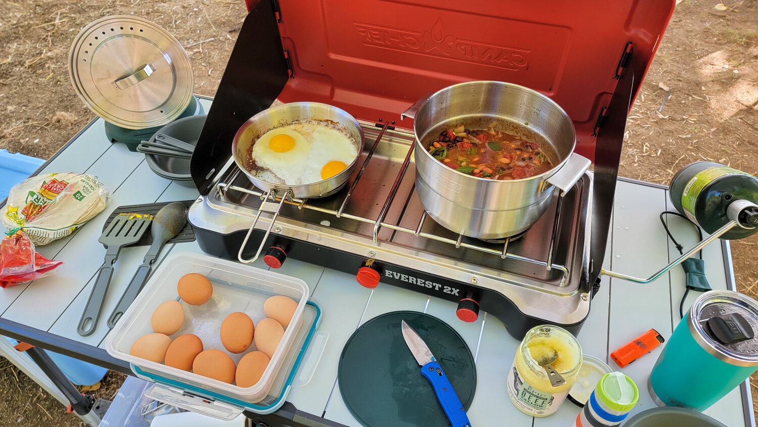 Top-down view of beans and eggs cooking on a camp stove